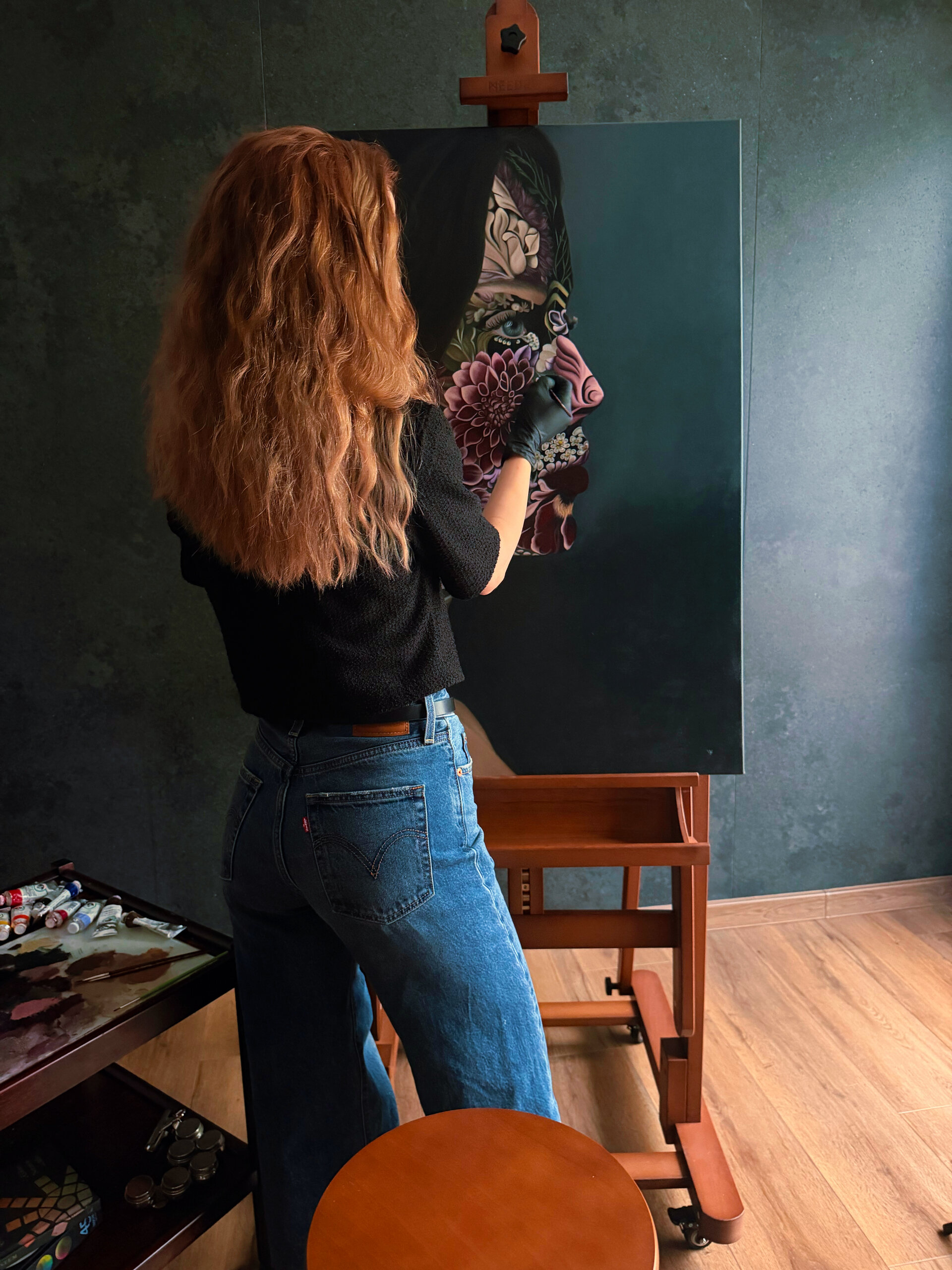 Maeve Vamy painting at her easel in her studio